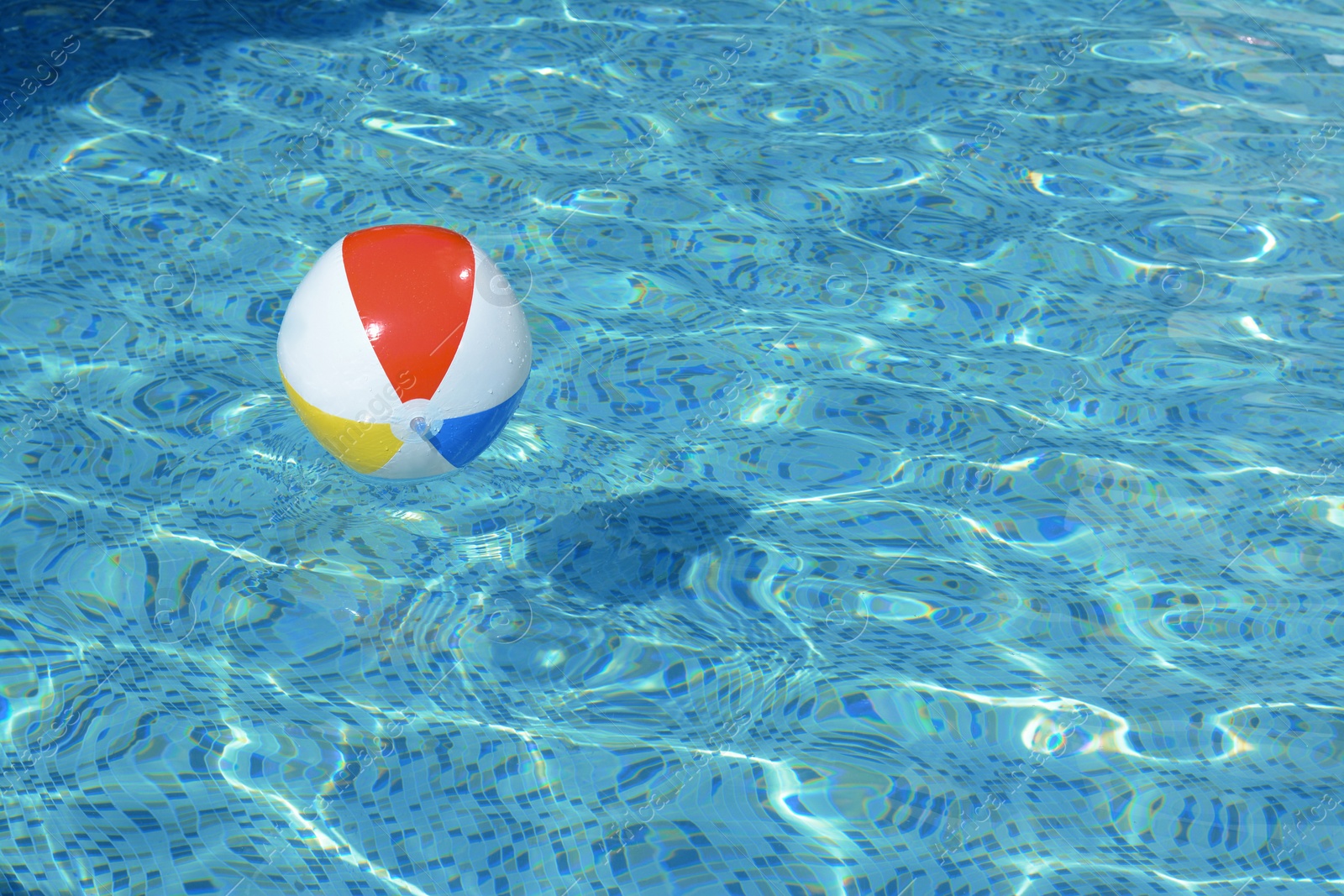 Photo of Inflatable beach ball floating in swimming pool, space for text