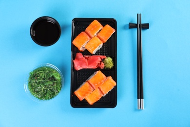 Flat lay composition with sushi rolls on color background. Food delivery