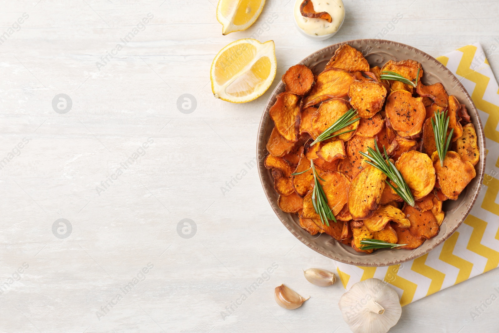 Photo of Flat lay composition with plate of sweet potato chips on light table. Space for text