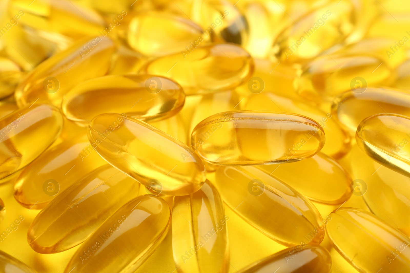 Photo of Many vitamin capsules on yellow background, closeup