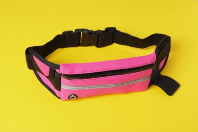 Photo of Stylish pink waist bag on yellow background
