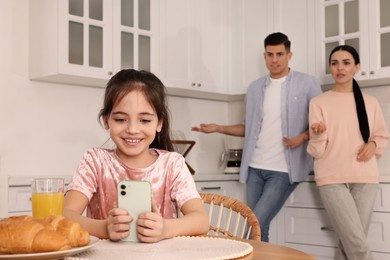 Photo of Internet addiction. Parents scolding their daughter while she using smartphone in kitchen