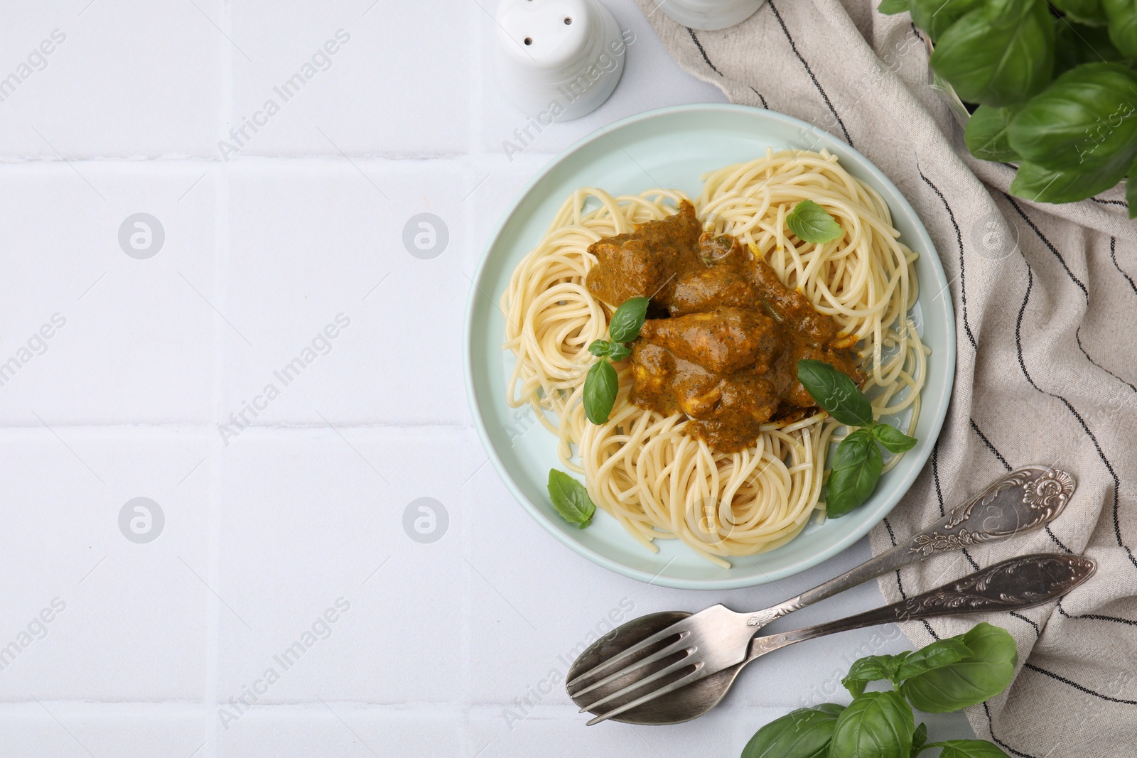 Photo of Delicious pasta and chicken with curry sauce served on white tiled table, flat lay. Space for text