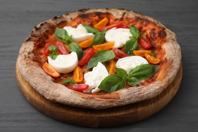 Photo of Delicious pizza with burrata cheese, tomatoes and basil on grey wooden table, closeup