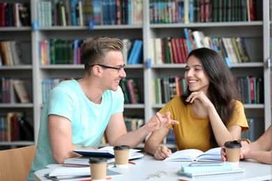 Young people discussing group project at table in library