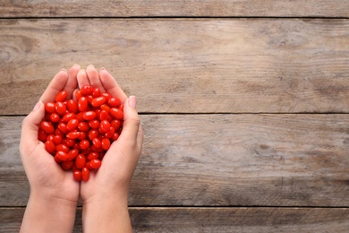 Photo of Woman holding fresh goji berries on wooden background, top view. Space for text