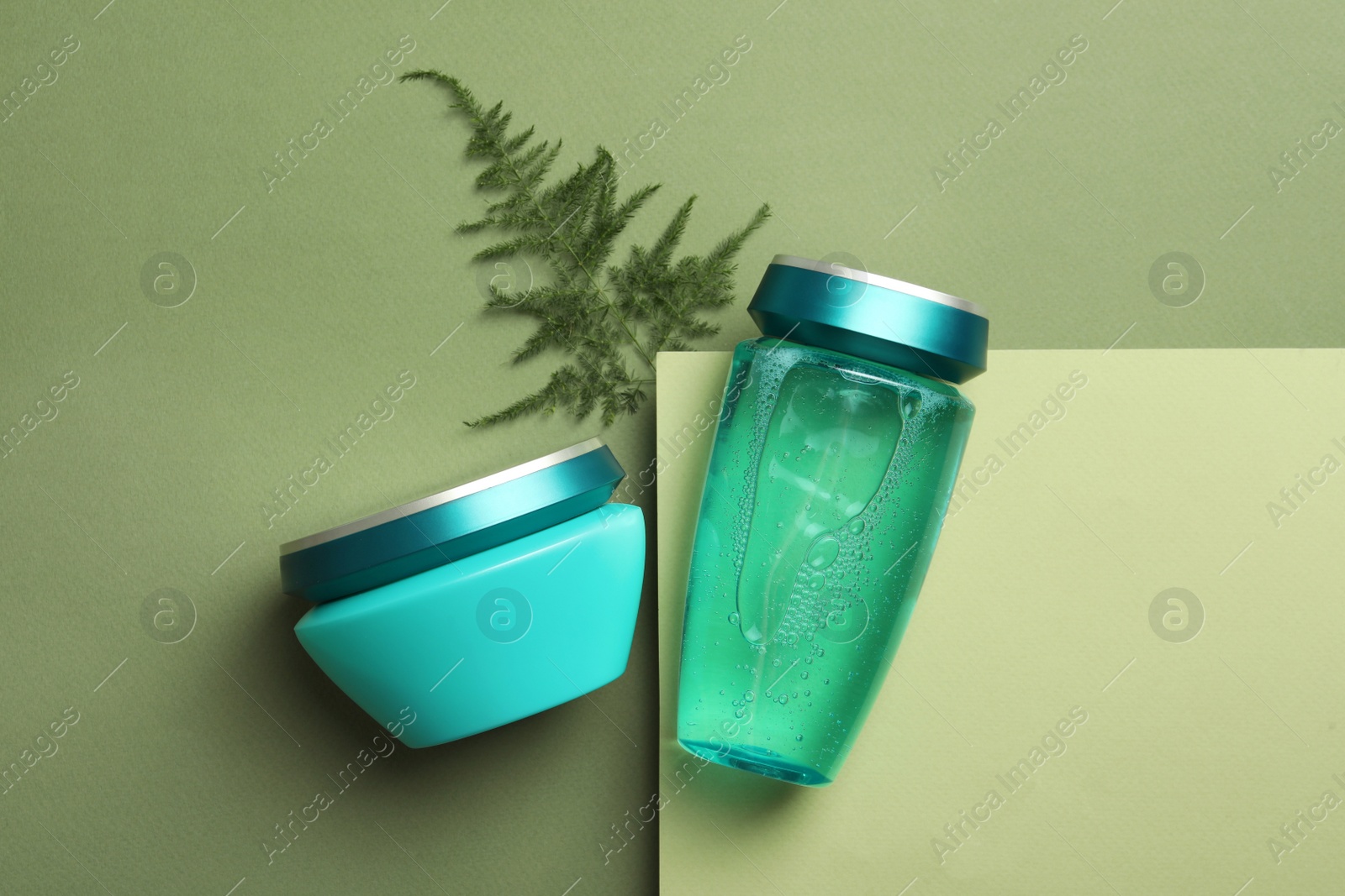 Photo of Hair care cosmetic products and leaf on green background, flat lay