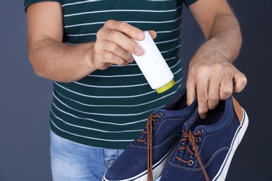 Man putting powder shoe freshener in footwear on color background, closeup