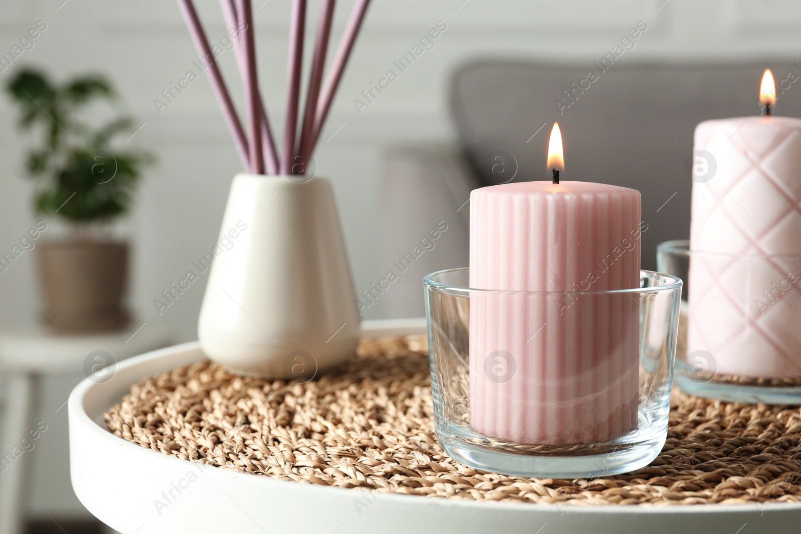 Photo of Burning candles and air reed freshener on table indoors, space for text