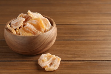 Photo of Delicious dried jackfruit slices on wooden table. Space for text