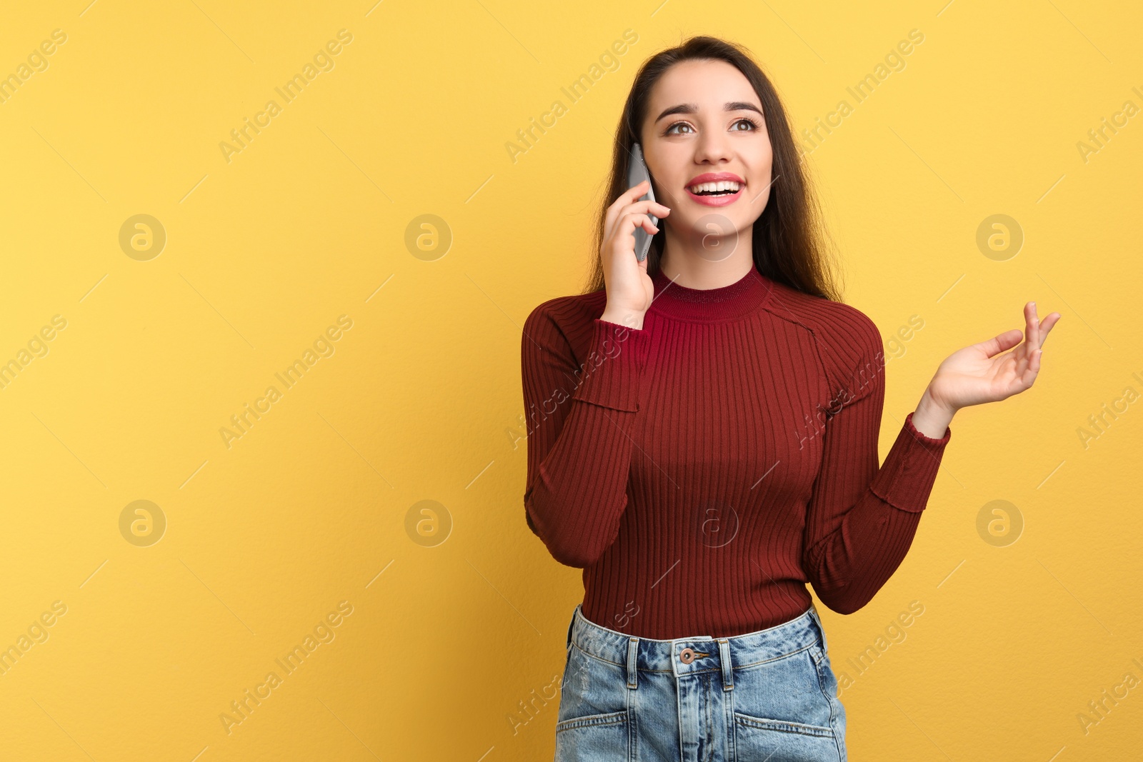 Photo of Young woman talking on phone against color background