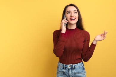 Photo of Young woman talking on phone against color background