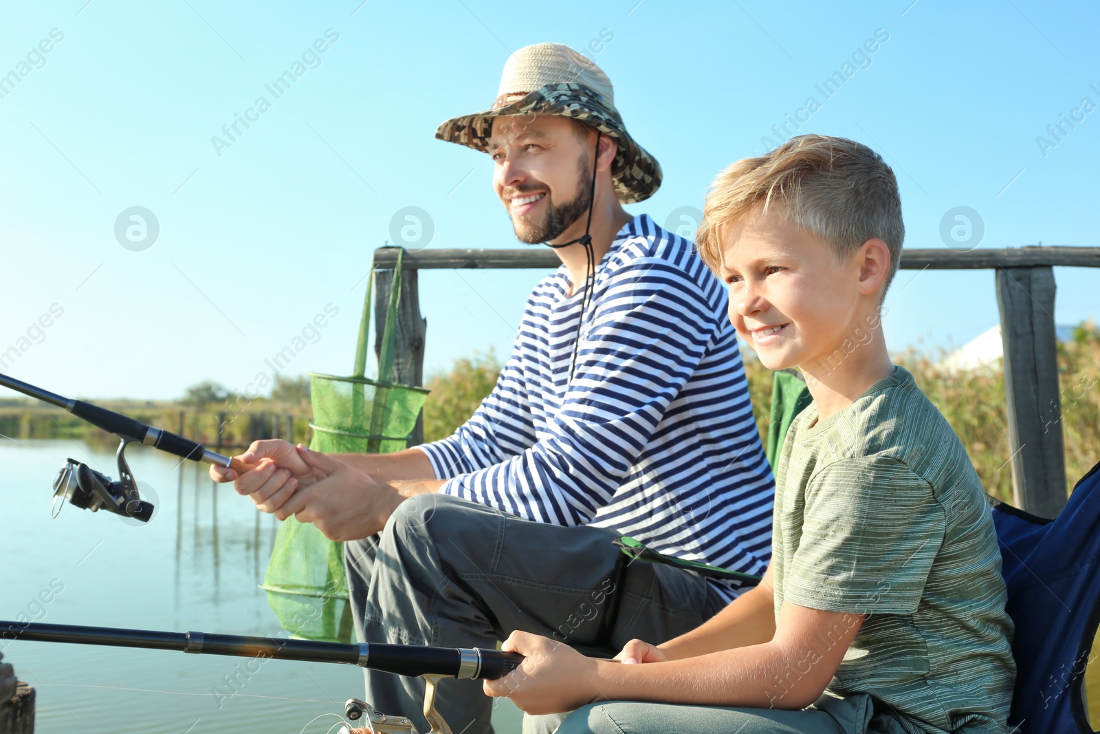 Photo of Father and son fishing together on sunny day