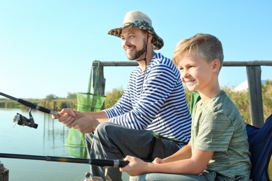 Father and son fishing together on sunny day