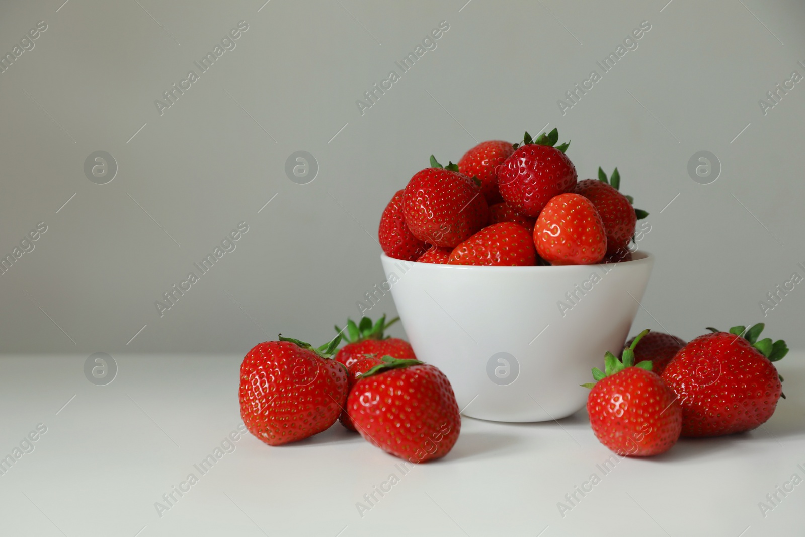 Photo of Fresh juicy strawberries on white table, space for text