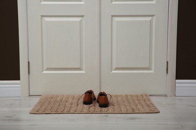 Photo of Stylish shoes on door mat in hall