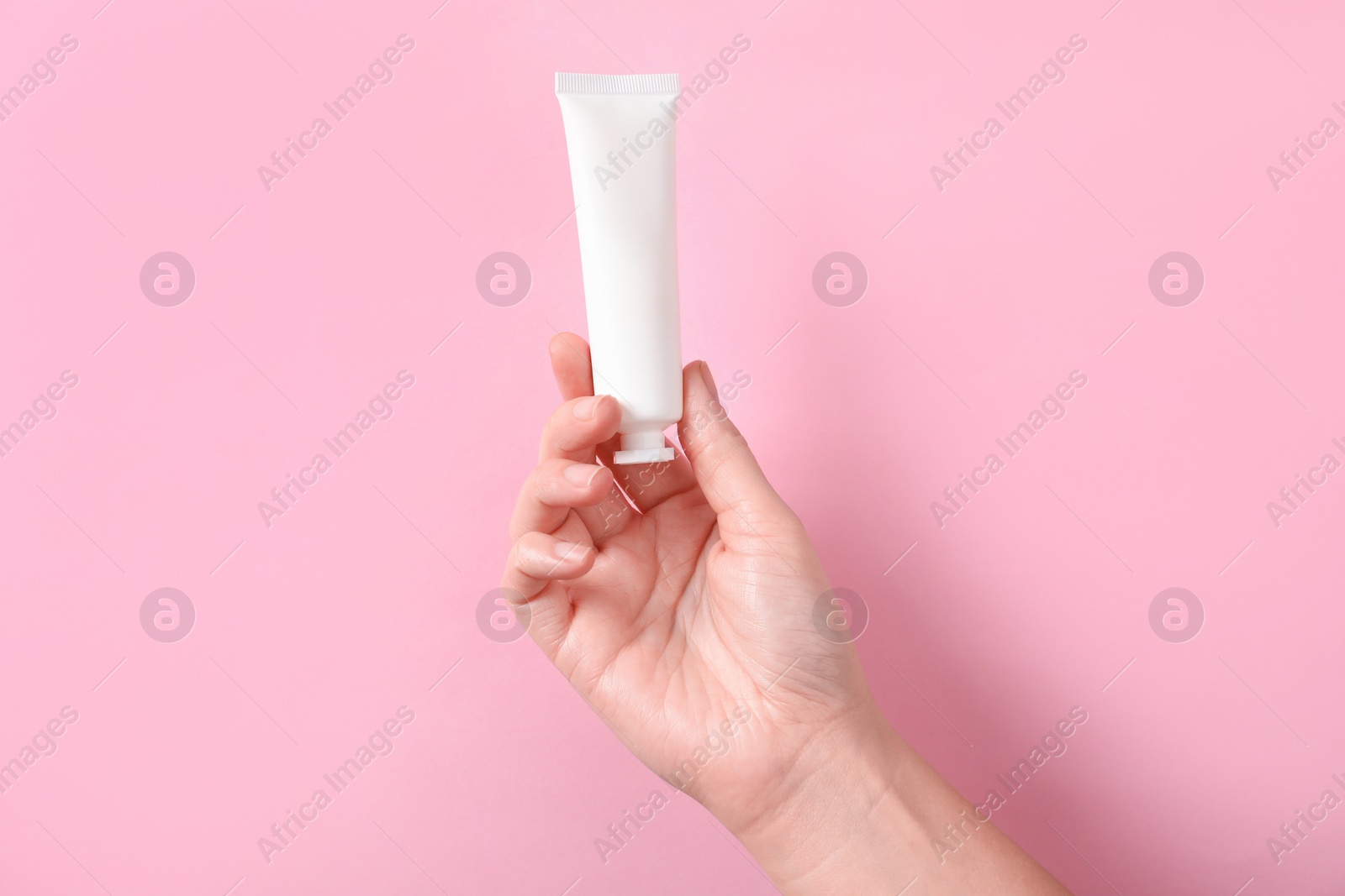 Photo of Woman with tube of hand cream on pink background, closeup