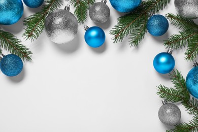 Photo of Christmas balls and fir tree branches on white background, flat lay. Space for text