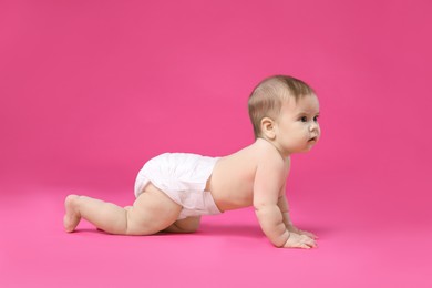 Photo of Cute little baby in diaper crawling on pink background