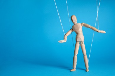 Photo of One wooden puppet with strings on light blue background. Space for text