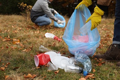 People with trash bags collecting garbage in nature, closeup