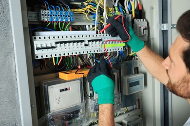 Electrician checking electric current with multimeter indoors, closeup
