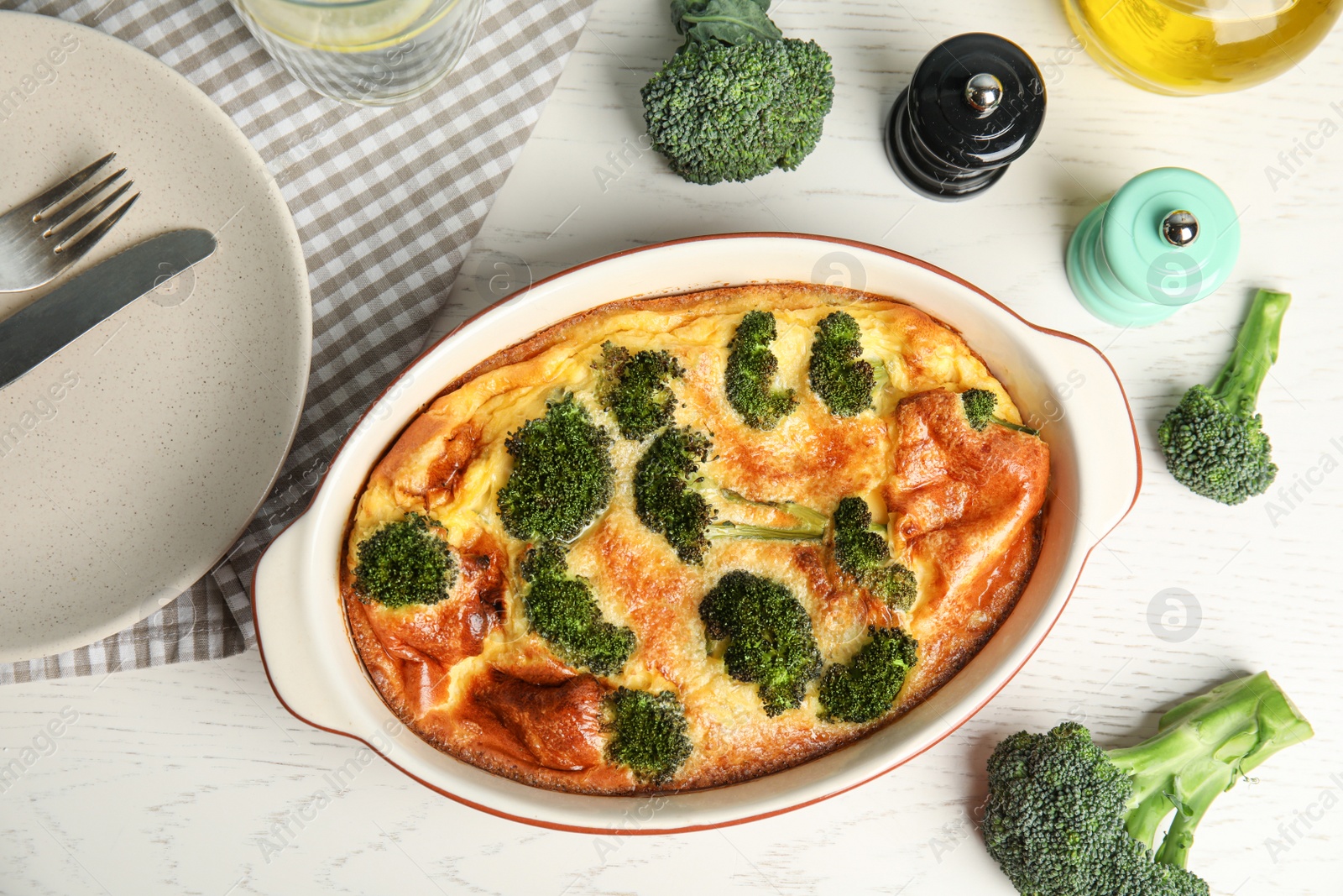 Photo of Tasty broccoli casserole in baking dish on white wooden table, flat lay