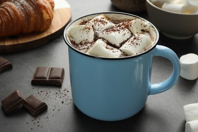 Photo of Delicious hot chocolate with marshmallows, cocoa powder and spoon on grey table, closeup