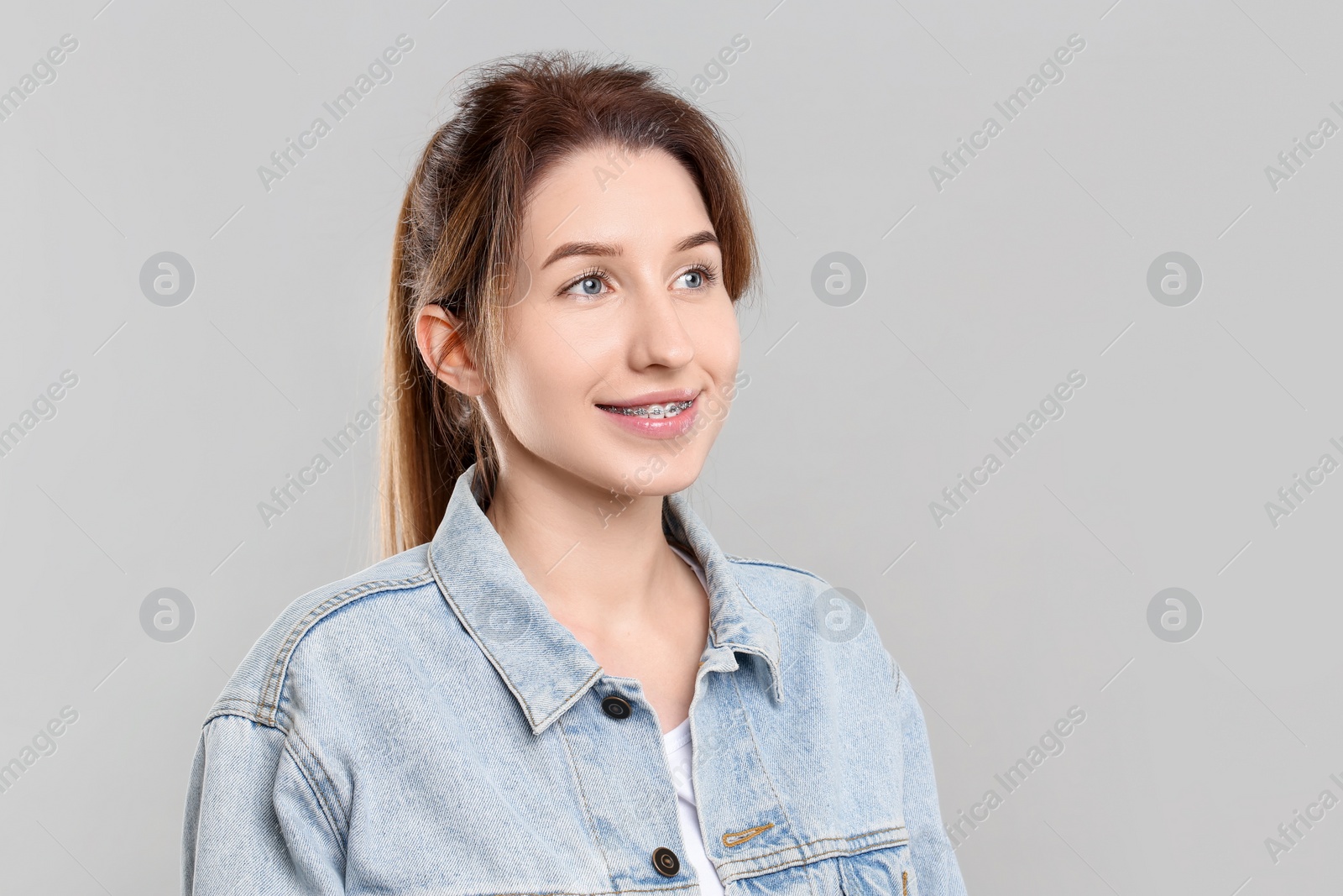 Photo of Portrait of smiling woman with dental braces on grey background