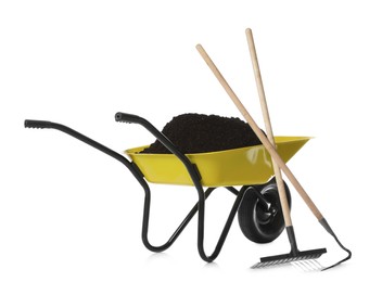 Photo of Wheelbarrow with soil, rake and hoe on white background. Gardening tools