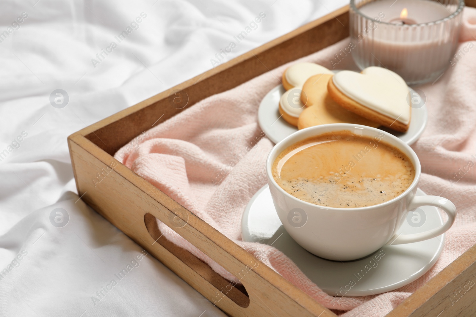 Photo of Wooden tray with coffee and cookies on bed. Romantic breakfast