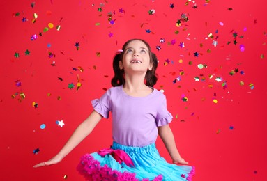 Adorable little girl and falling confetti on red background