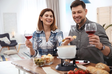 Happy couple enjoying fondue dinner at home