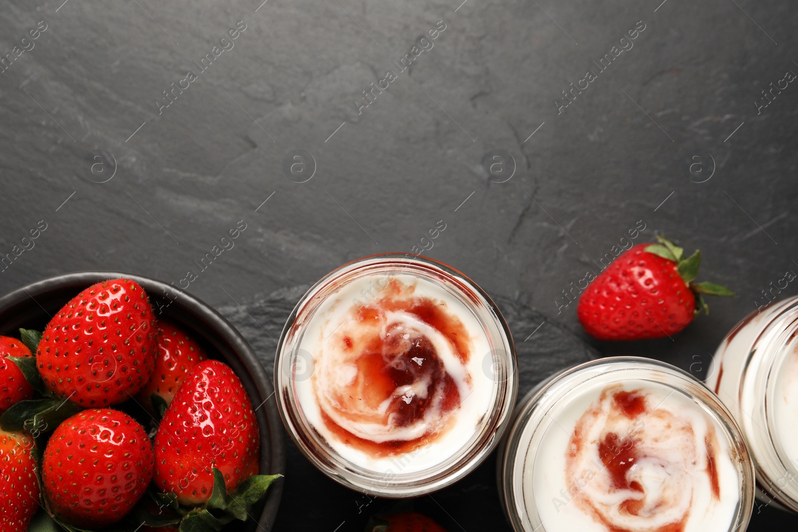 Photo of Tasty yoghurt with jam and strawberries on black table, flat lay. Space for text