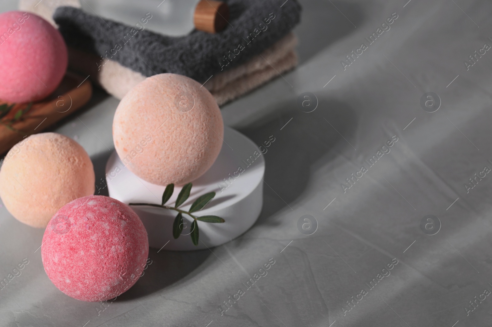 Photo of Beautiful aromatic bath bombs and green twig on grey table, space for text