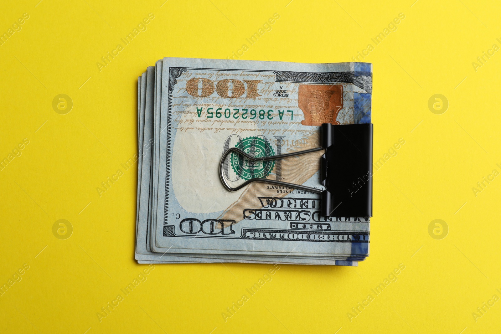 Photo of Dollar banknotes with paper clip on yellow background, top view