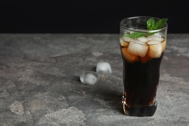 Photo of Refreshing soda drink with ice cubes and mint on grey table. Space for text