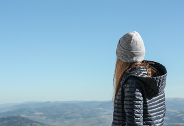 Photo of Woman in warm clothes looking at beautiful mountain landscape