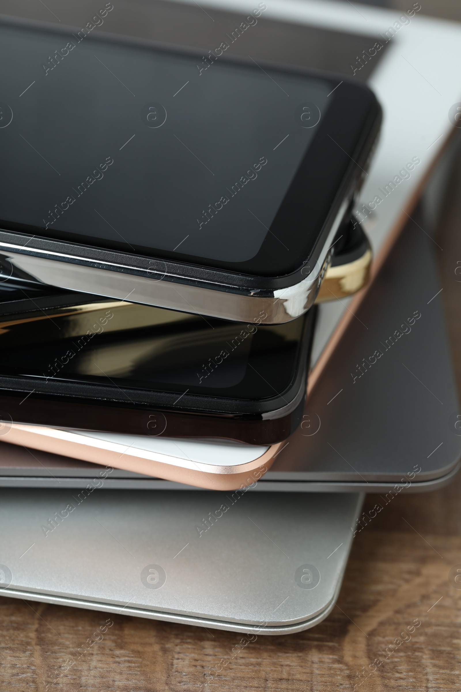 Photo of Stack of electronic devices on wooden table, closeup