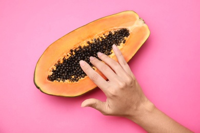 Young woman touching half of papaya on pink background, top view. Sex concept