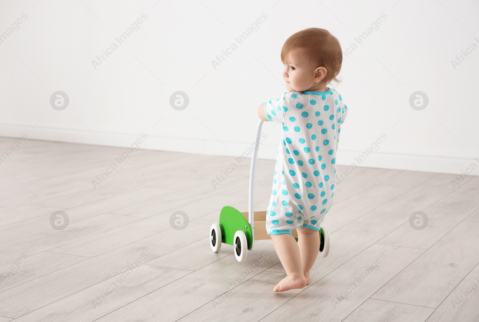 Photo of Cute baby playing with toy walker, indoors