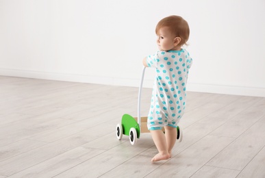 Cute baby playing with toy walker, indoors