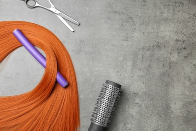 Photo of Flat lay composition with hair lock and tools on grey background. Space for text