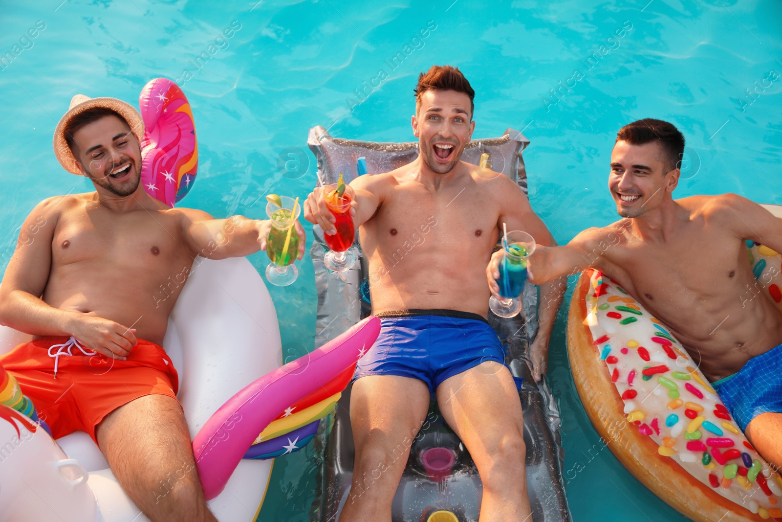 Photo of Happy young friends with refreshing cocktails relaxing in swimming pool