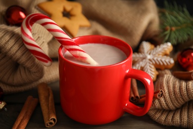 Photo of Cup of tasty cocoa with Christmas candy cane on wooden table