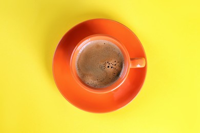 Photo of Coffee in cup on yellow background, top view