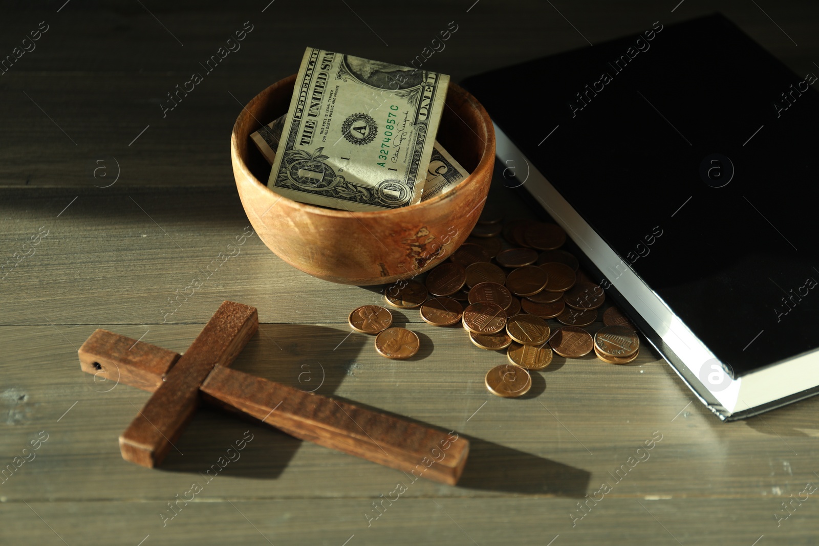 Photo of Donate and give concept. Bowl with coins, dollar banknotes, cross and Bible on wooden table