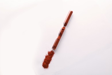 Photo of Glass tube with paprika on white background, top view