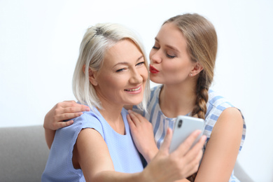 Happy mother and daughter taking selfie at home