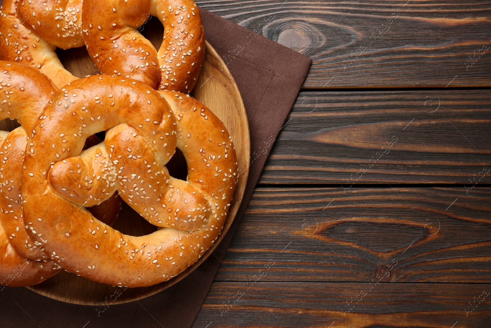 Photo of Tasty freshly baked pretzels on wooden table, top view. Space for text